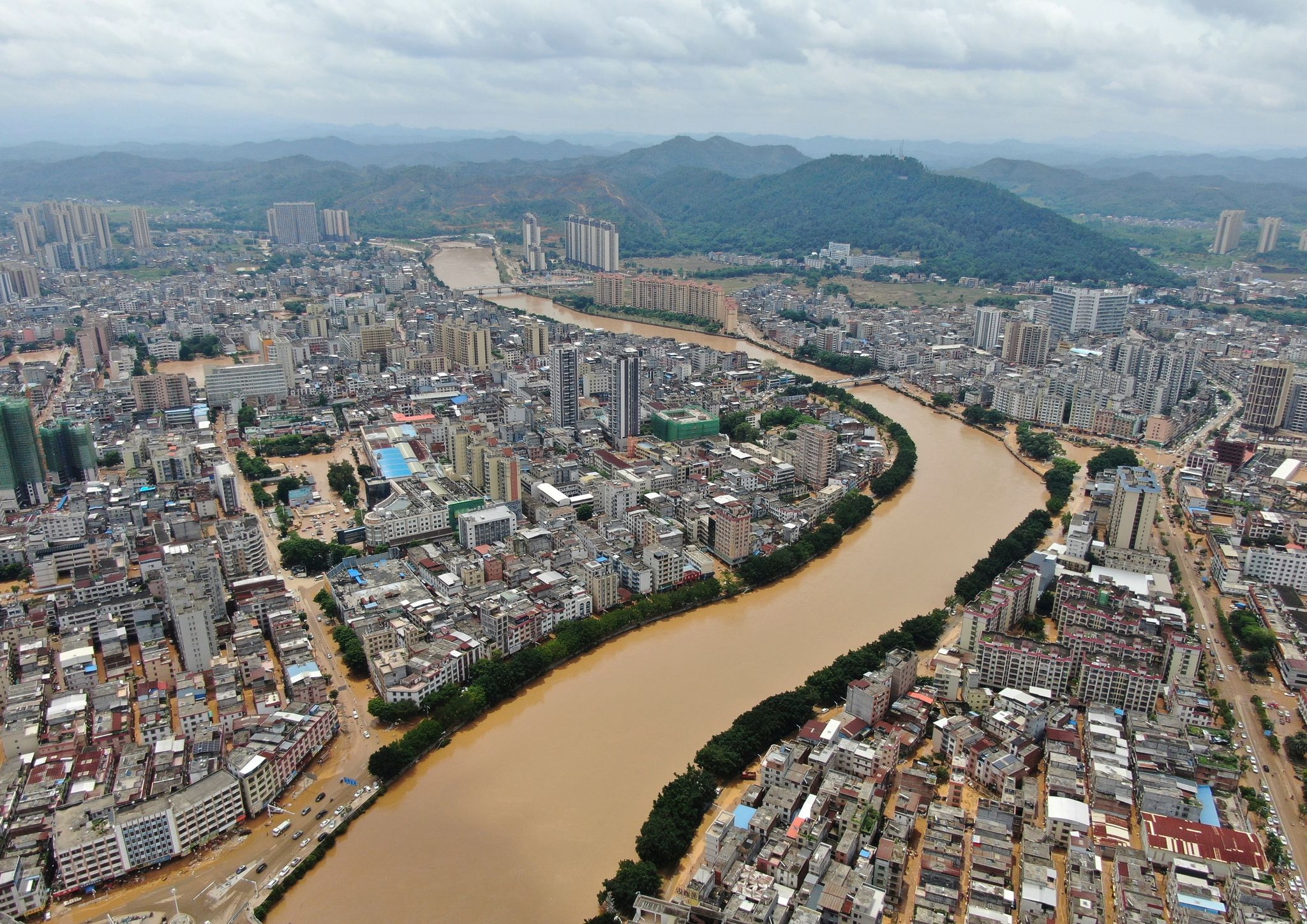 A river overflows in southern China, stranding people and turning streets into canals